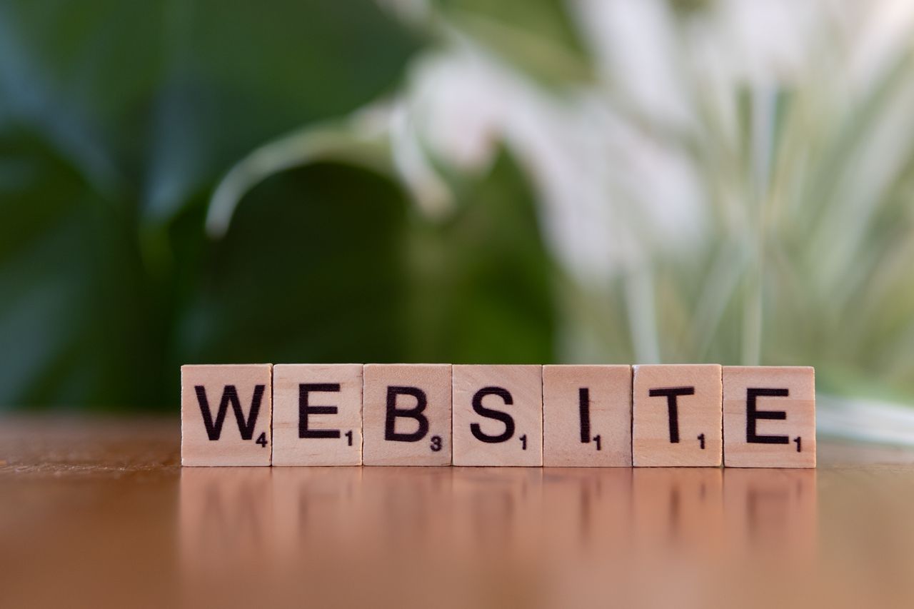 Home Scrabble tiles on a wooden surface forming the word 'Website', symbolizing digital communication.