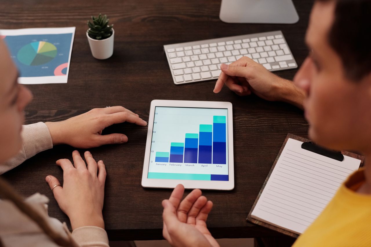 Home Team members discussing digital graphs on a tablet in a modern office setting.