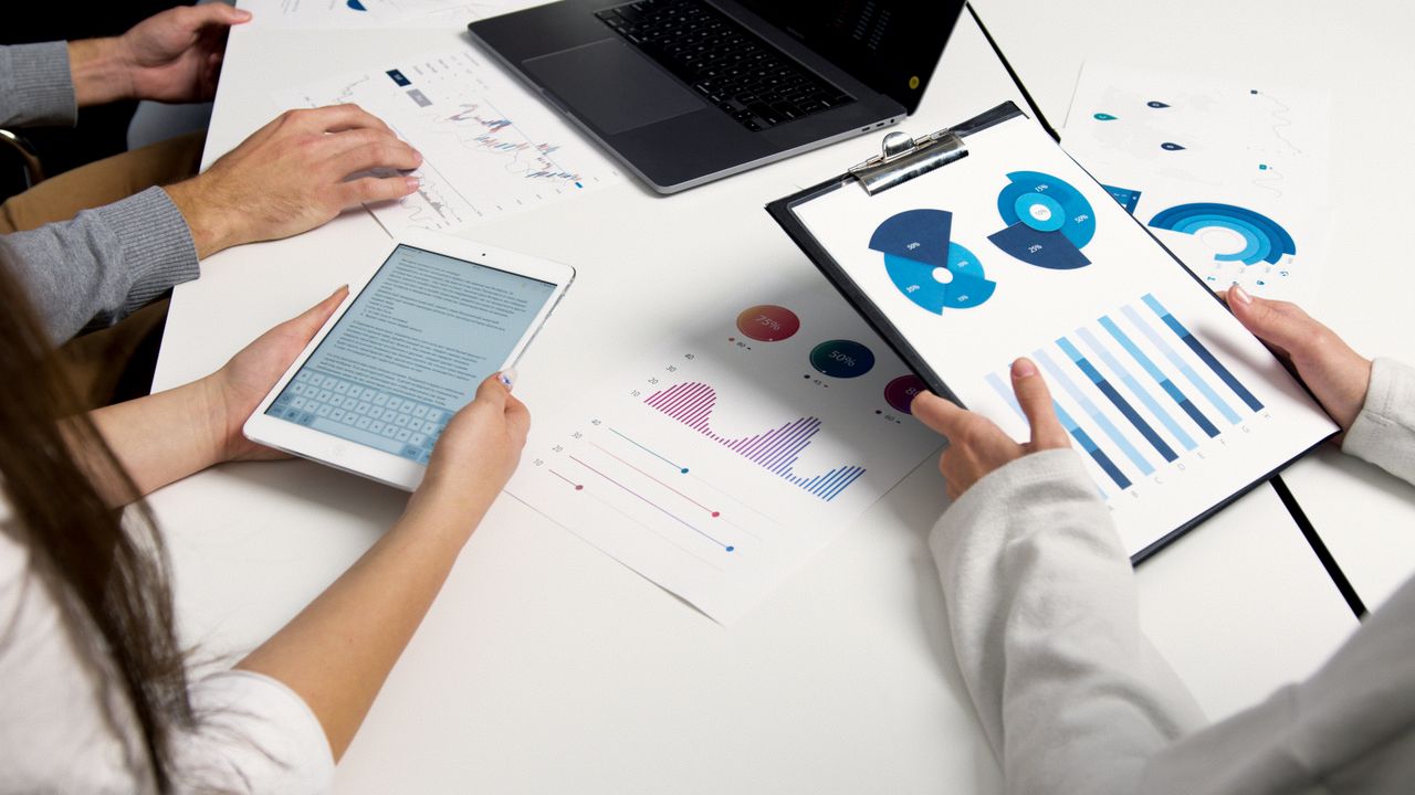 Services-03 Team analyzing financial charts and digital reports during a business meeting.