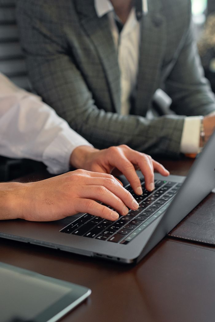 Business professionals working on a laptop in an office setting, showcasing teamwork and technology.